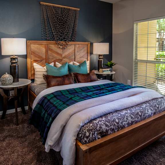 A bedroom with a bed, two lamps, and a chair.