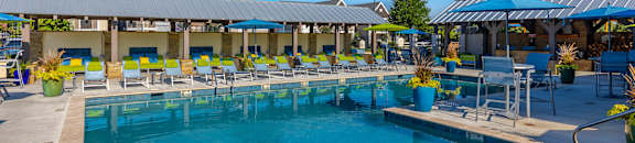 A large outdoor swimming pool with loungers and umbrellas at Reserve of Bossier City Apartment Homes in Bossier City, Louisiana