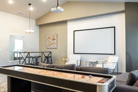 A shiny air hockey table is in the middle of a room with a couch and chairs.