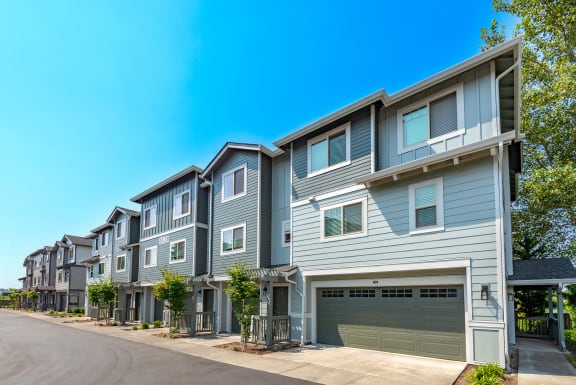 a row of townhomes with blue siding and brown doors