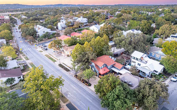 A street view of a residential area with houses and trees.