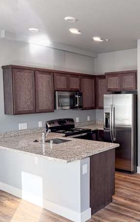 A kitchen with brown cabinets and a granite countertop at ONE18 West Street Residential Apartments, Reno Nevada