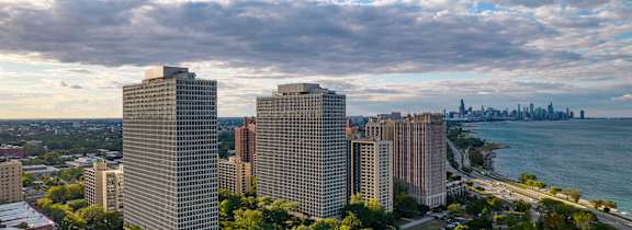 A cityscape with buildings, trees, and a body of water in the background.