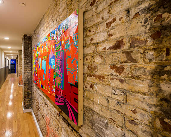 A long hallway with a brick wall and a colorful painting on the wall.