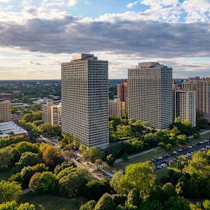 A cityscape with buildings, trees, and a body of water in the background.