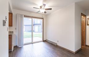 A room with a ceiling fan and sliding glass doors.