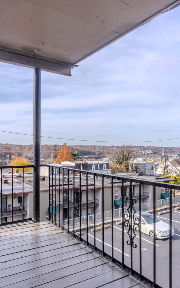 the balcony has a view of the parking lot and the city