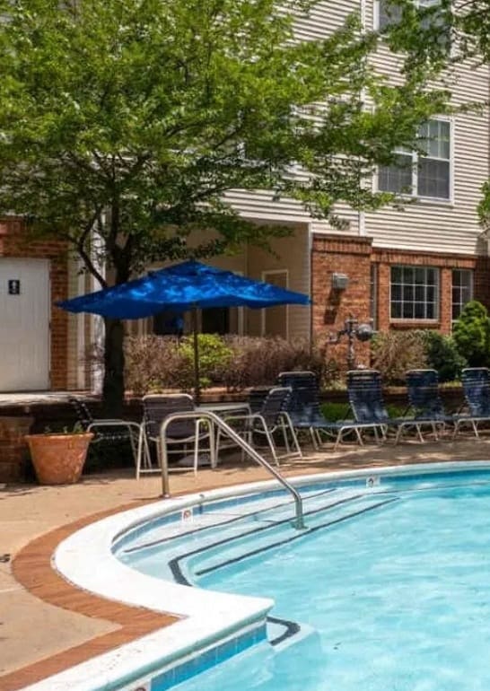 a swimming pool with chairs and umbrellas in front of a building at The Morgan Apartment Homes, Maryland