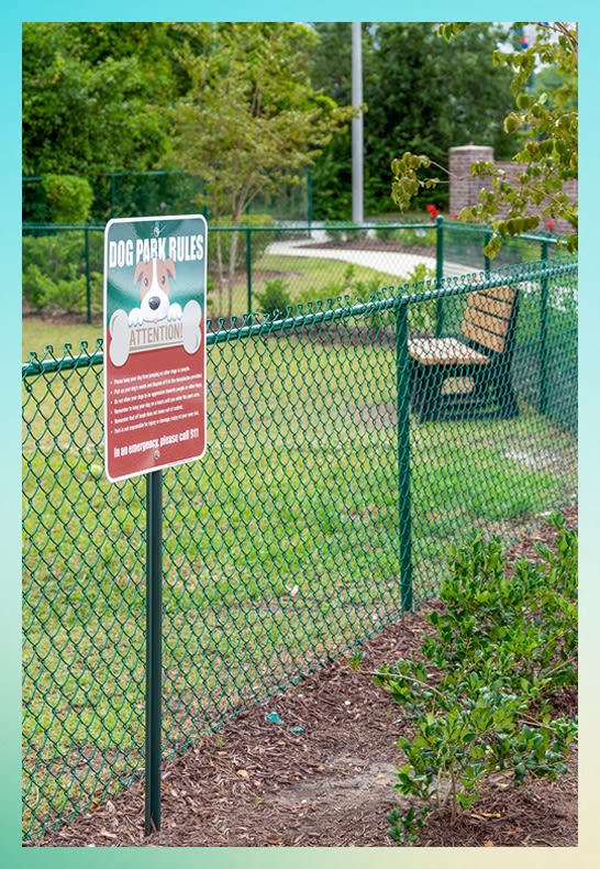 a dog park rules sign on a chain link fence at River Oaks, Little River