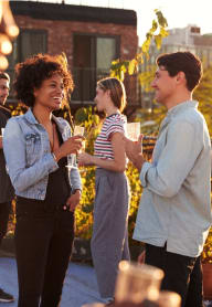 a group of people talking and drinking wine at an outdoor event