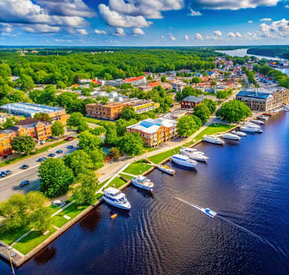 A boat is sailing on a river with a town in the background.