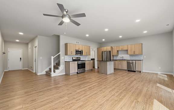 A spacious kitchen and living room with wooden floors and modern appliances.