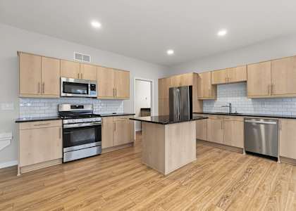 A kitchen with wooden cabinets and a black refrigerator.
