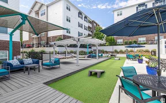 a patio with blue chairs and umbrellas and a green turf
