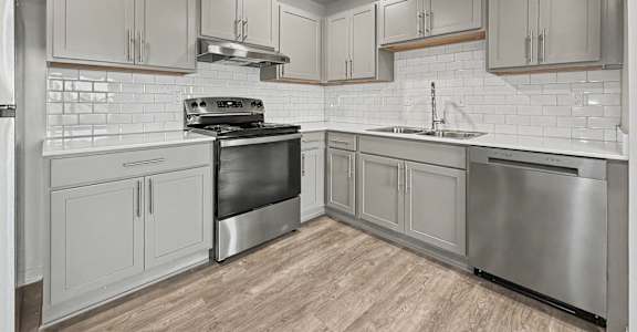 A modern kitchen with stainless steel appliances and wooden flooring.