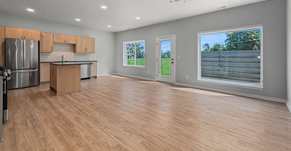 A spacious kitchen with wooden floors and a ceiling fan.