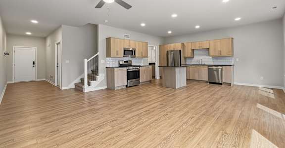 A spacious kitchen and living room with wooden floors and modern appliances.