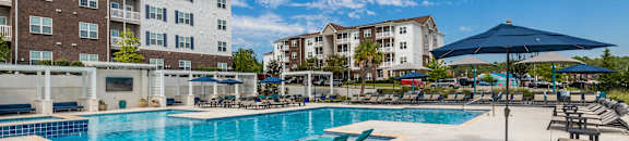 our apartments have a large swimming pool with lounge chairs and umbrellas at The Met Apartment Homes, Hattiesburg, 39402