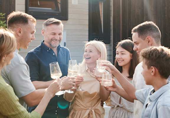 A group of people are toasting with glasses in front of a wooden building  at 445 Cleveland Apartments in Atlanta, Georgia,