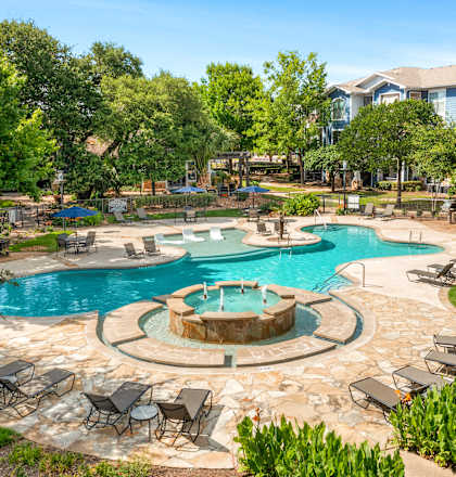 A large outdoor swimming pool surrounded by lawn chairs and trees.
