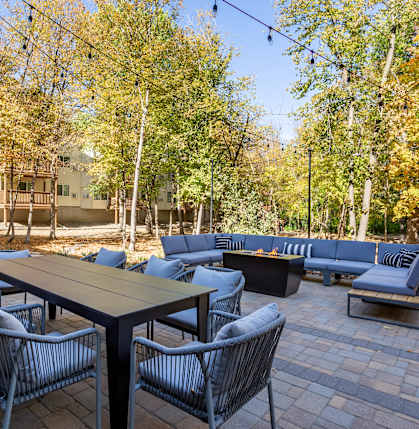 a patio with couches tables and chairs and trees