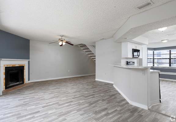 an empty living room with a fireplace and a ceiling fan