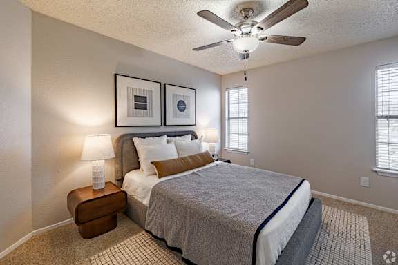 A bedroom with a bed, a ceiling fan, and two wall lamps. at Highland Park, Texas, 76132