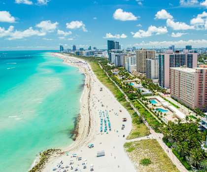 A beachfront view with a row of hotels and a city skyline in the distance.