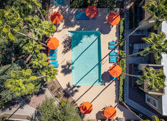 a birds eye view of a swimming pool and patio with orange umbrellas