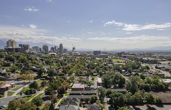 A cityscape with buildings and trees under a blue sky.