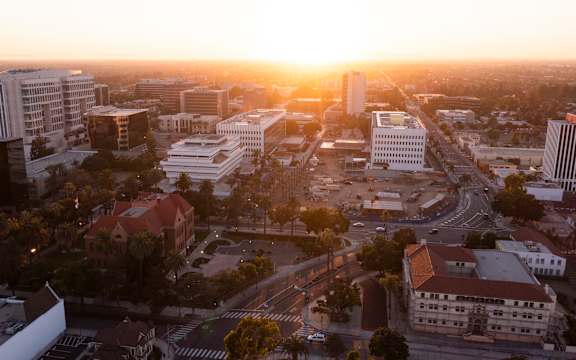 A cityscape at sunset with buildings and roads.