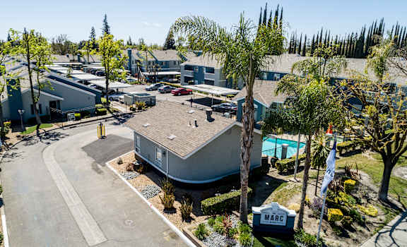 A sunny day at the Mare community with a pool and palm trees.