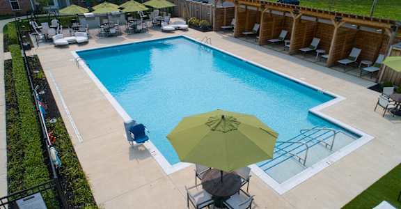 a swimming pool with a green umbrella and chairs around it
