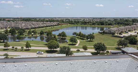 an aerial view of a pond in a neighborhood with houses