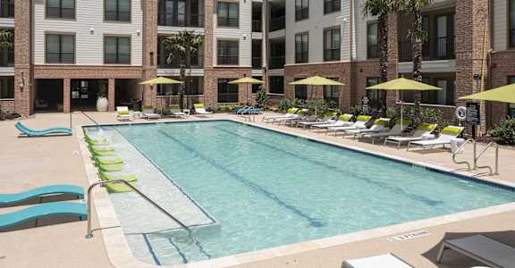 a swimming pool with lounge chairs and a building in the background