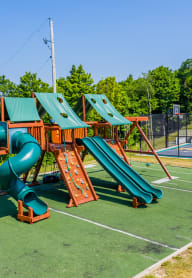 a playground with a swing set and slides on a basketball court
