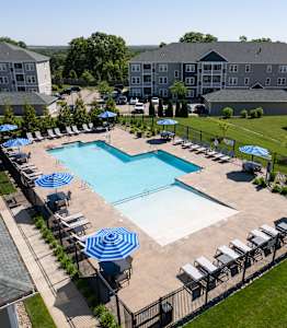 A large swimming pool surrounded by blue umbrellas and lounge chairs.