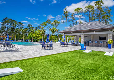A large swimming pool with lounge chairs and a building in the background.