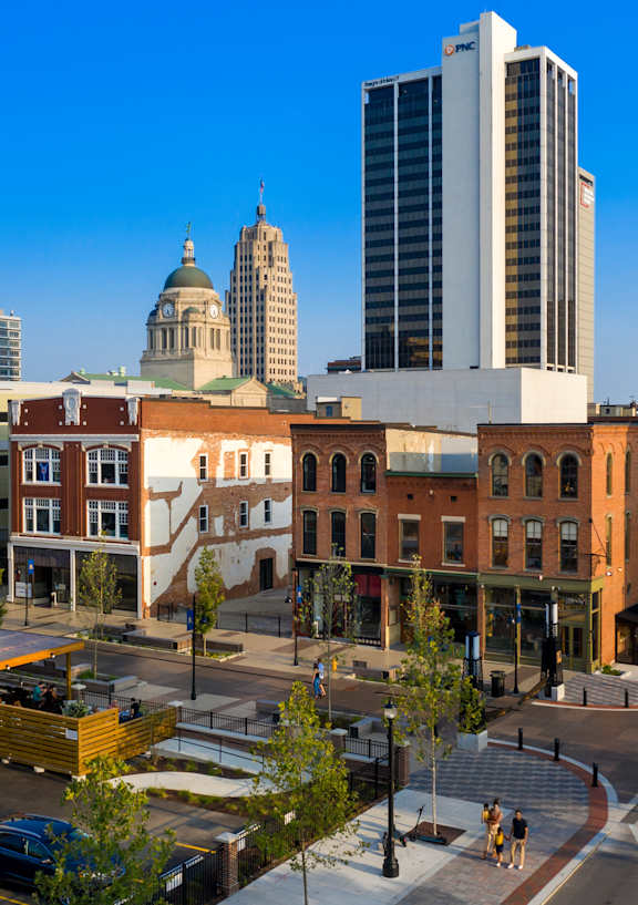 A cityscape with a mix of modern and older buildings, a large open square, and a clear sky.
