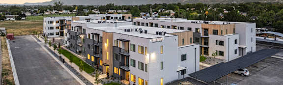 A modern apartment complex with a parking lot in front.