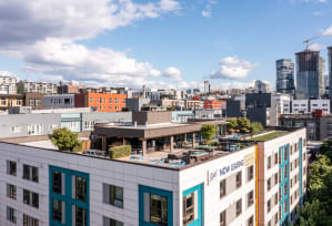 an aerial view of a large white building with a green roof and a city in the background