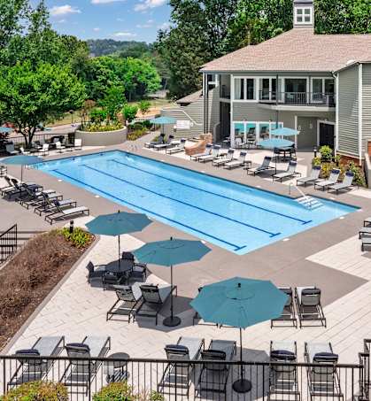 a swimming pool with lounge chairs and umbrellas in front of a building