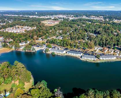 A serene aerial view of a lake surrounded by lush greenery and buildings.