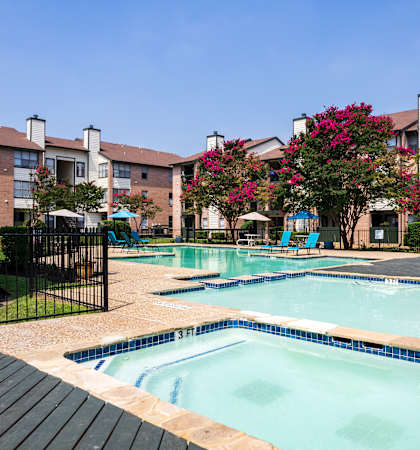 A pool surrounded by a black fence and a building in the background.