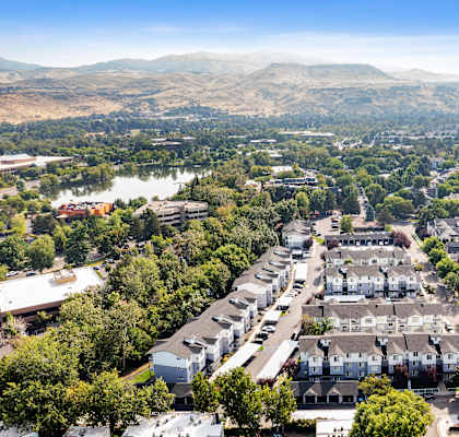 A bird's eye view of a residential area with houses and a lake in the distance.