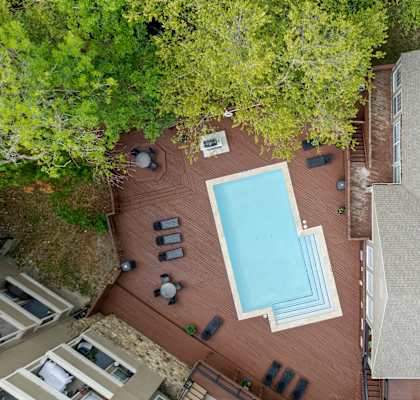 A swimming pool surrounded by a few chairs and umbrellas.