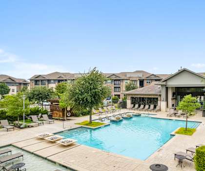 A swimming pool surrounded by a patio with chairs and umbrellas.