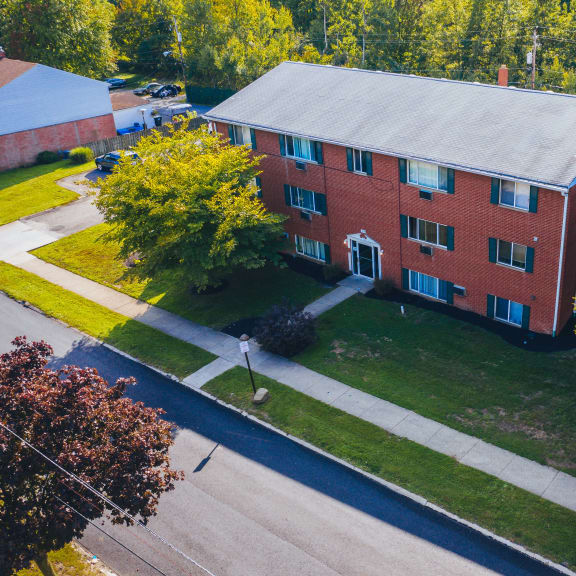 an aerial view of a brick building with green grass and trees