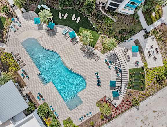 A pool surrounded by a patio and a garden.