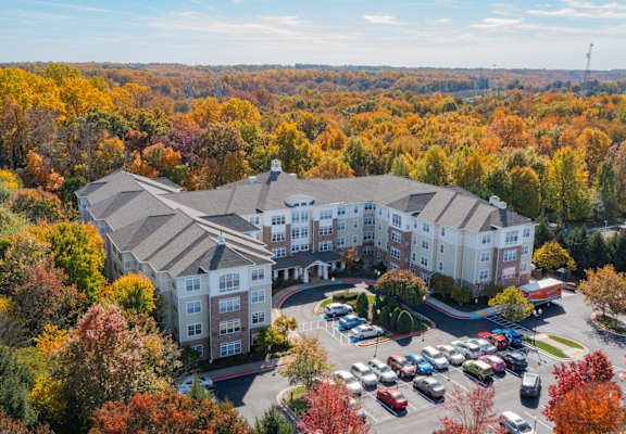 A large white building surrounded by trees in autumn.